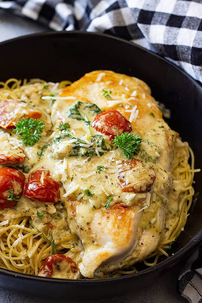 Close up of Creamy Tuscan Chicken in a bowl on top of pasta.
