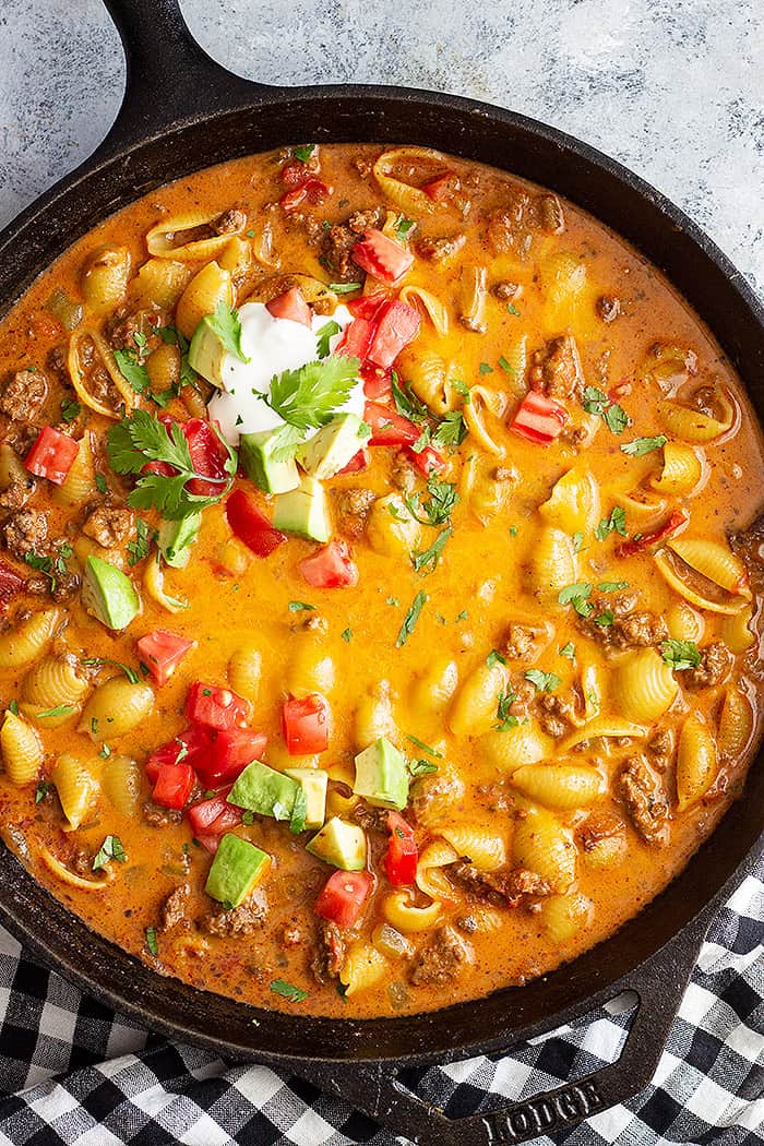 Top down picture of taco pasta in a large skillet. Topped with taco toppings. 