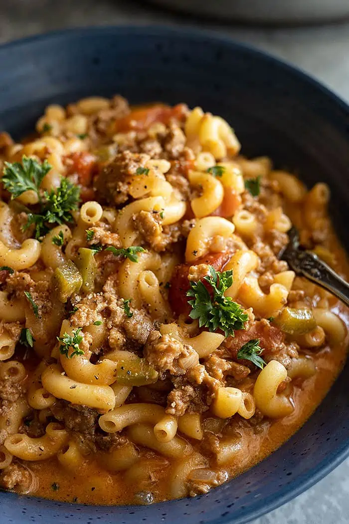 extreme closeup: American goulash in a blue bowl garnished with parsley
