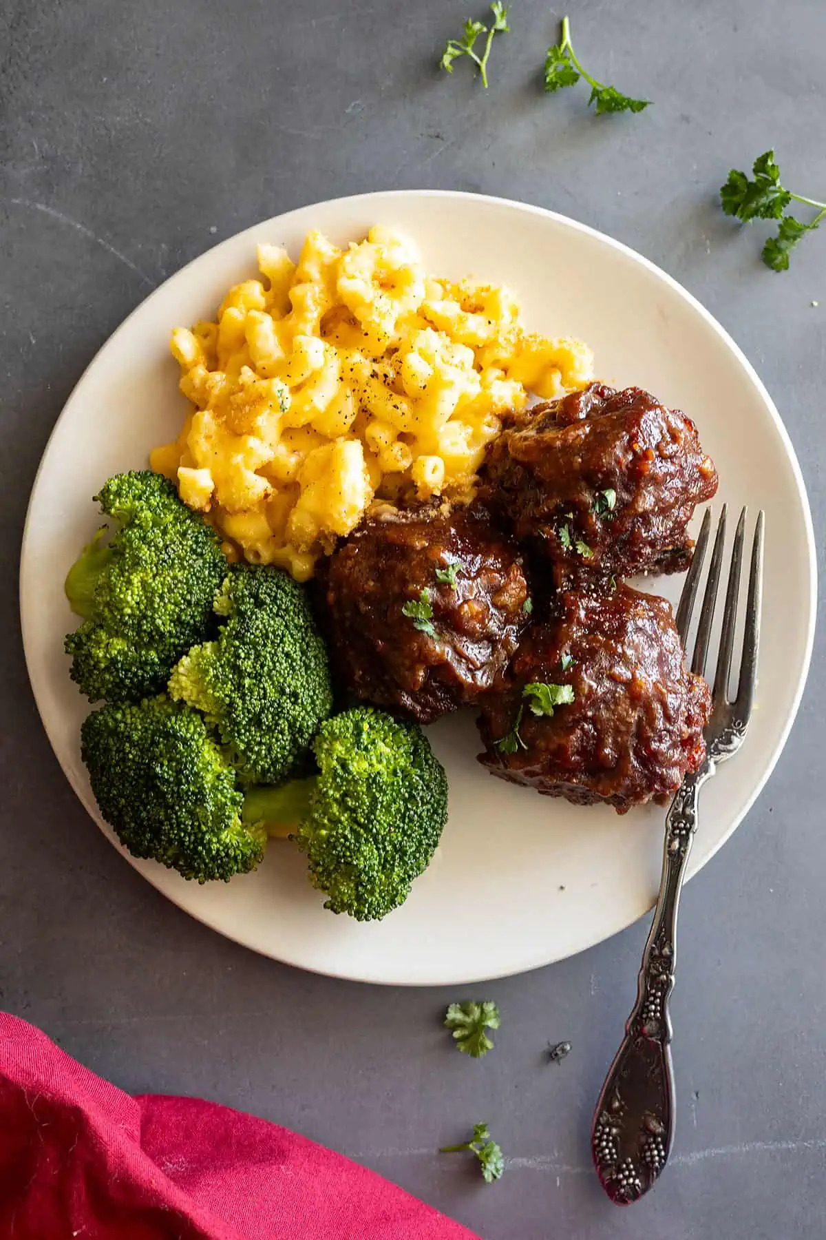 overhead: BBQ meatballs on a cream plate with a fork off to the side. Red napkin in the corner